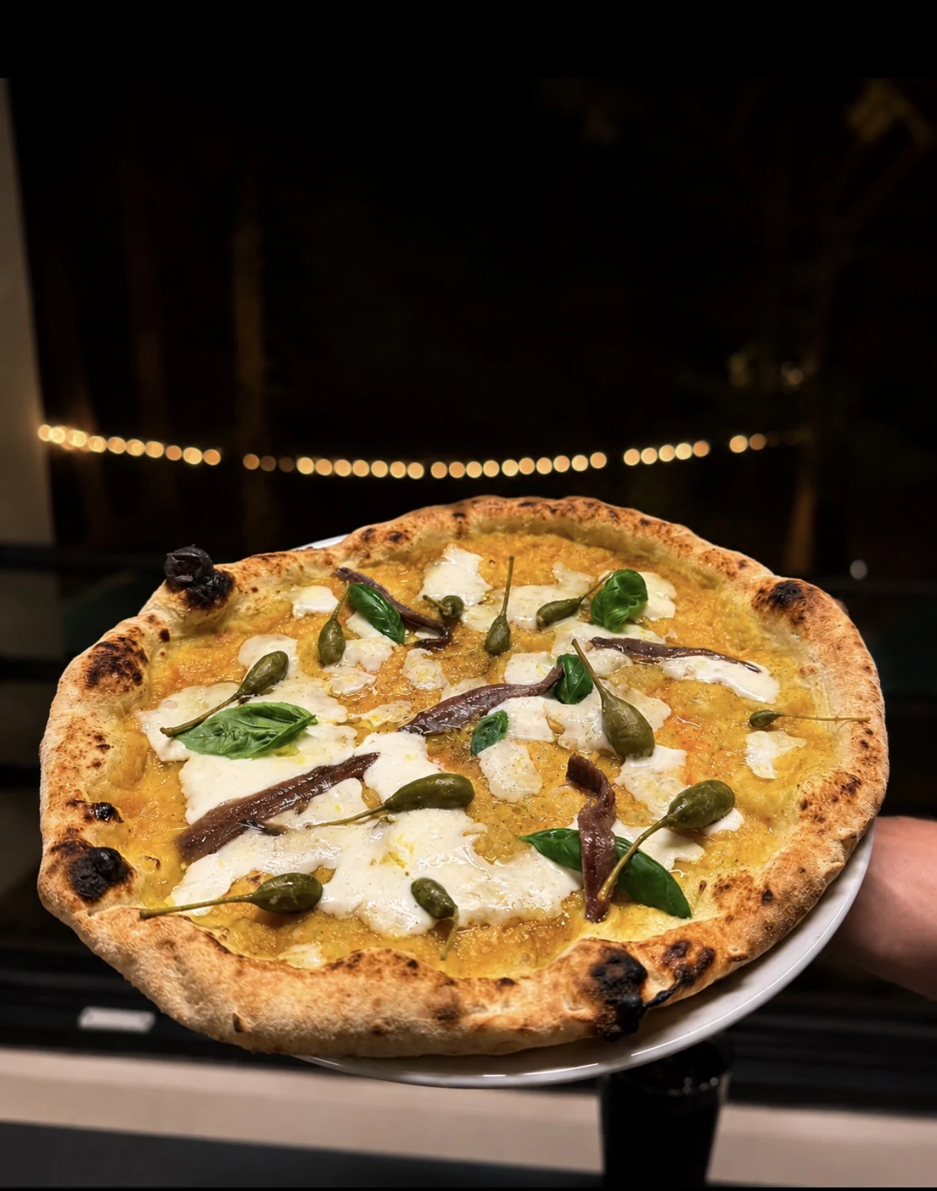 Una pizza di Ca’ de Luna appena sfornata, con basilico, acciughe e capperi.